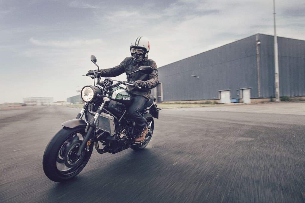Rider wearing a quilted retro leather motorcycle jacket on a vintage-style Yamaha motorcycle