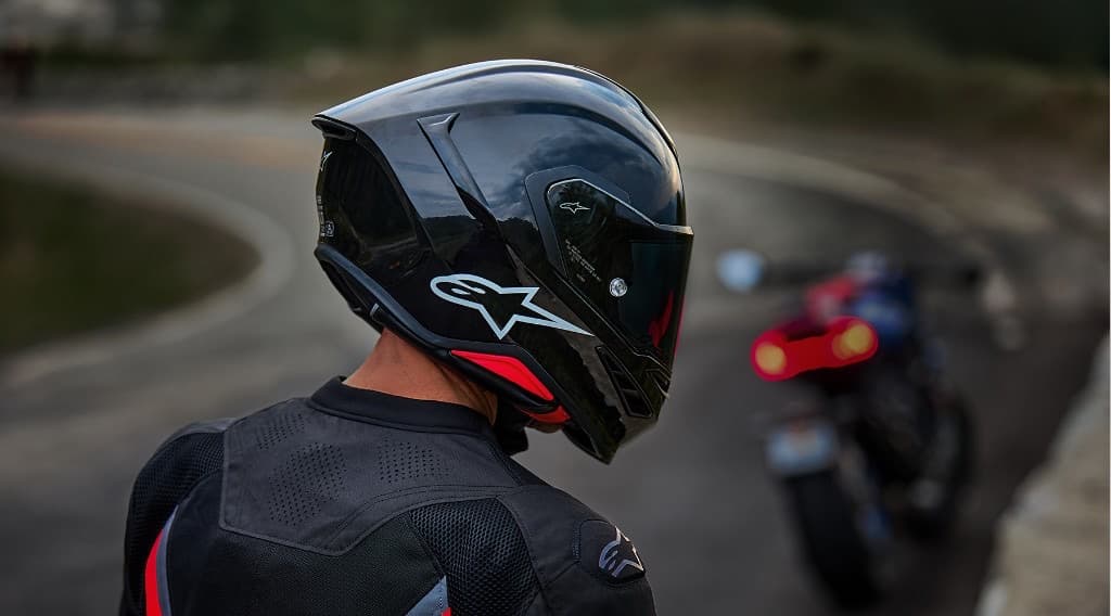 Close-up of a modern black full-face Alpinestars motorcycle helmet with a tinted visor on a rider